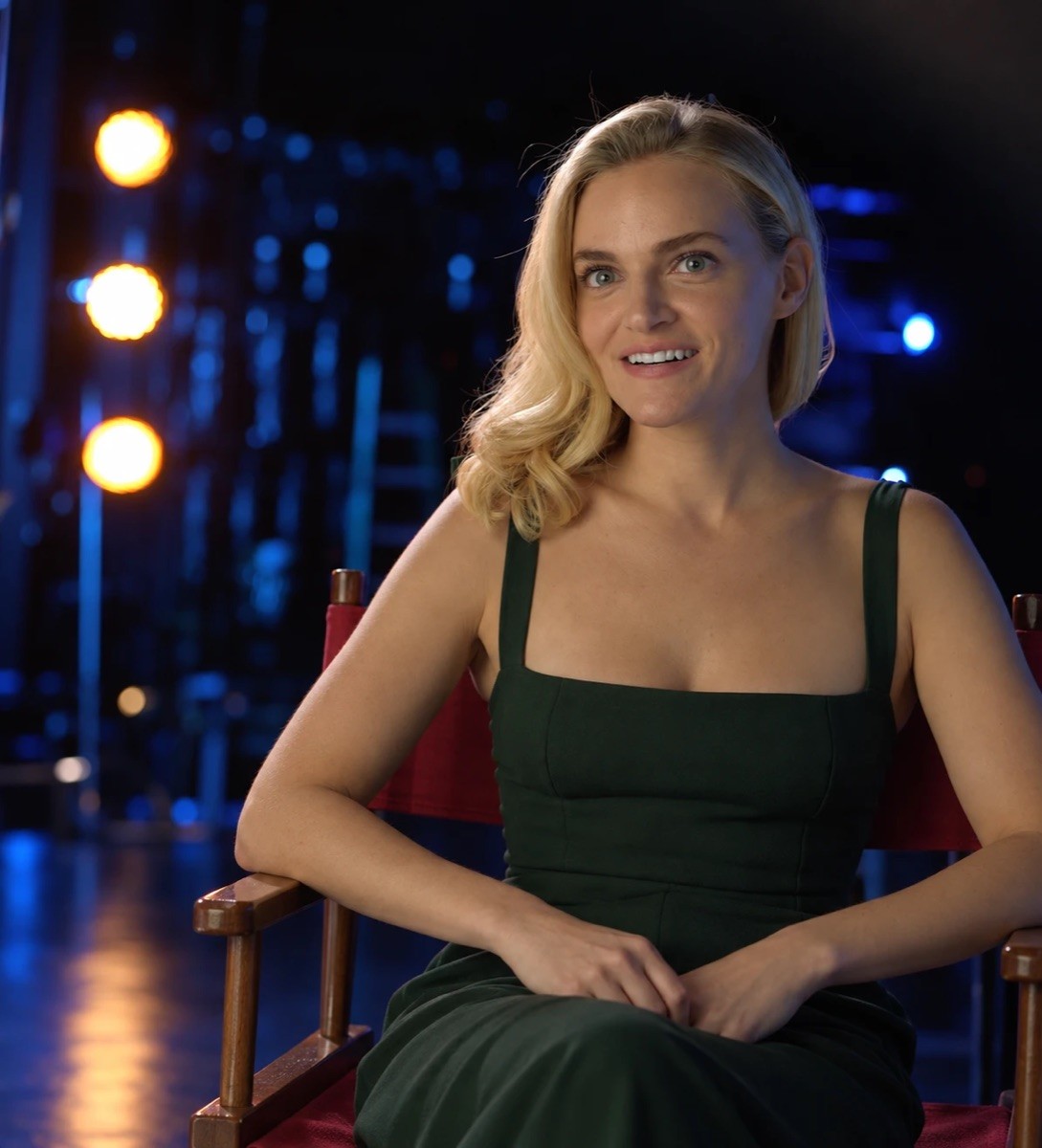 Madeline Brewer seated in a director’s chair on a dark stage