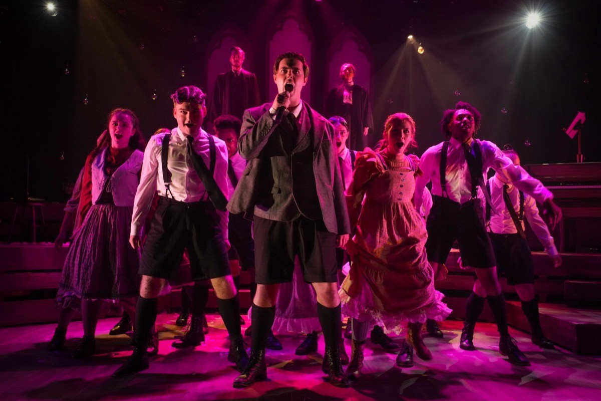 AMDA musical theatre students performing an ensemble number under magenta stage light
