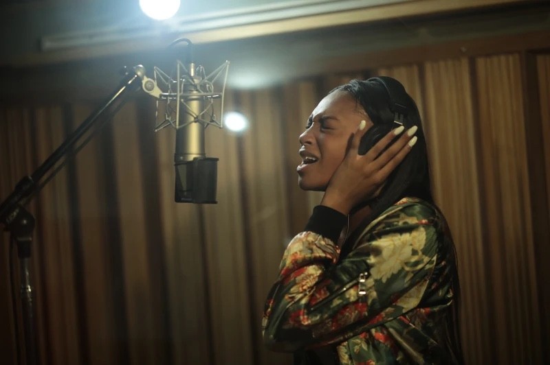An AMDA student singing into a studio microphone with headphones on