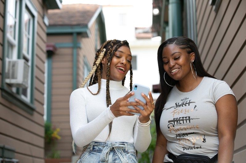 A pair of new AMDA students view a smartphone outside the Los Angeles campus bungalows