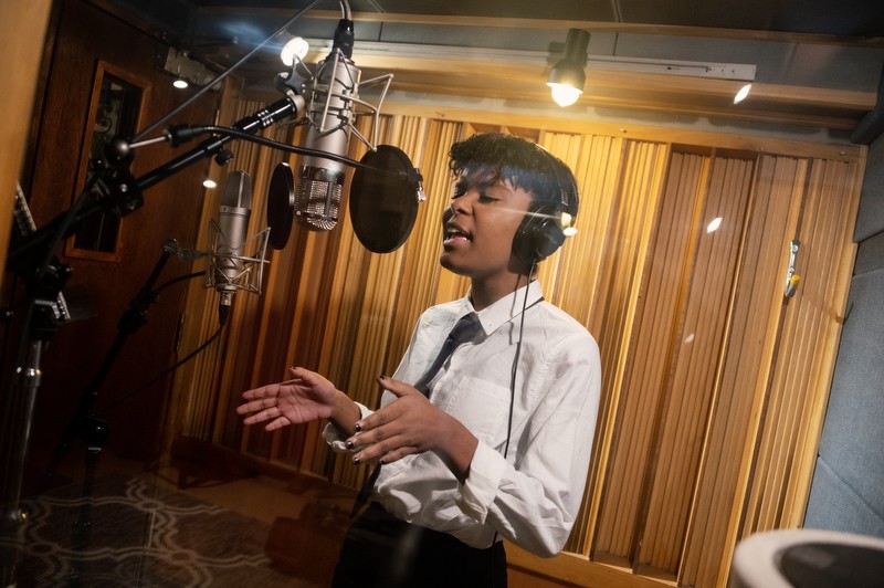 AMDA student sings into microphones in a recording studio sound booth